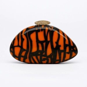 Detail of orange and black acrylic evening clutch with artistic lines and gold clasp