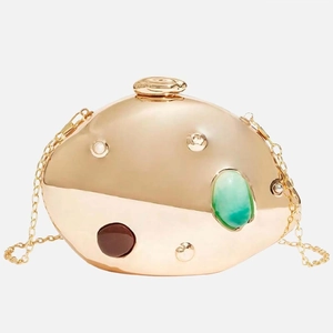 Detail of golden pebble-shaped evening clutch featuring large gemstones and fine chain