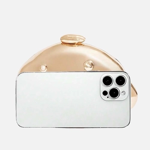Size comparison of a dome-shaped rose gold evening clutch bag next to a smartphone