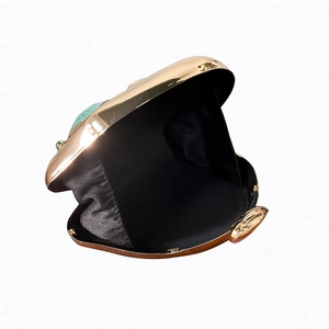 Detailed top view of an open gold evening clutch with turquoise stone inlay and black lining