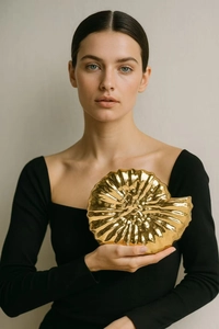 Macro view of a luxury golden nautilus shell clutch bag with metallic glossy finish