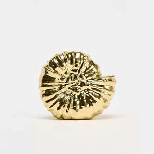 Macro detail of the golden snail shell clutch bag with a high-polished metallic texture