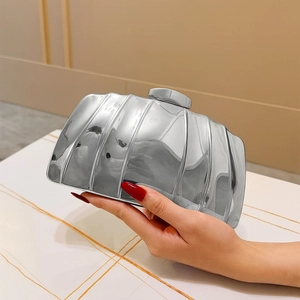 Silver metallic clutch bag with vertical striped shell design held by a model