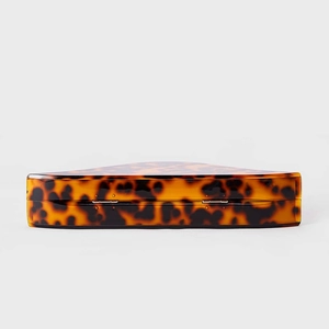 Close-up of tortoiseshell acrylic shell clutch bag featuring golden metal hinges