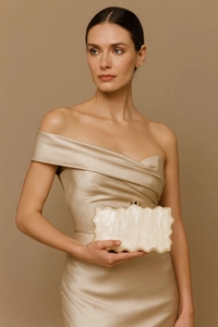 Detail of ivory acrylic evening clutch with marble texture and gold metal clasp