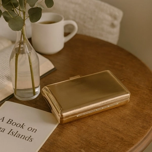 Elegant gold metal rectangular clutch bag with striped texture on a cozy wooden desk