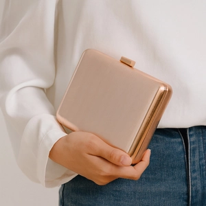 Detail of rose gold hard shell evening clutch with vertical metallic texture and clasp