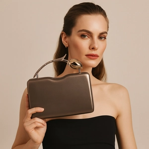 Detail of elegant champagne gold clutch with an artistic tulip-shaped metal handle