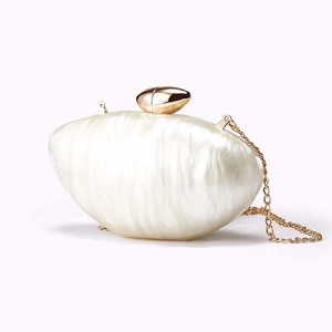 Detail of ivory acrylic evening clutch featuring pearlescent texture and gold spherical clasp
