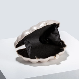 Detail of a pearl shell evening bag with golden clasp and soft black fabric lining