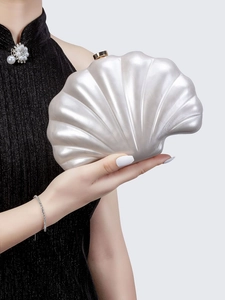 Detail of shell-shaped acrylic evening clutch with gold clasp and radial wavy texture