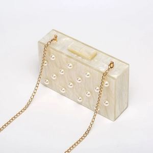 Makro-Detail der weißen Acryl-Clutch mit Marmorstruktur und elegantem Perleneinsatz