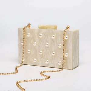 Detailansicht der Acryl-Clutch mit Kunstperlen-Akzenten und goldener Kettenriemen