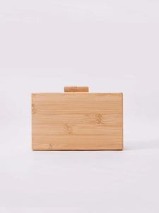 Detail of rectangular bamboo clutch featuring natural wood grain and cylindrical clasp