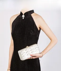 Detail of pearl white shell evening clutch with wave texture and gold ball clasp