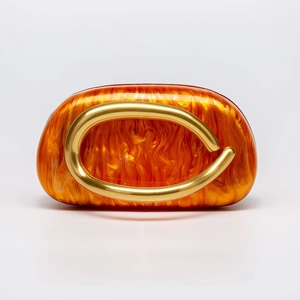 Detail of orange amber acrylic shell evening clutch with large gold metal round handle