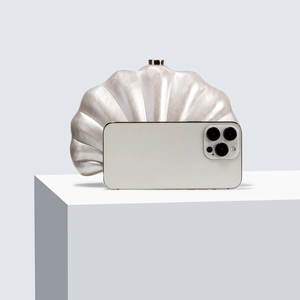 Elegant pearl-finish shell clutch bag with gold clasp shown next to a smartphone