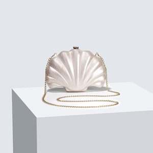 Elegant white shell shape acrylic evening clutch bag with gold chain strap on display