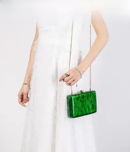 Dettaglio della pochette in acrilico verde con trama marmorea e catena dorata