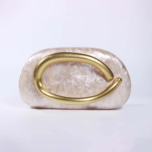 Detailed view of pearl acrylic shell clutch with luxury matte gold circular handle