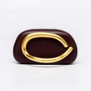 Close-up of a burgundy acrylic clutch featuring a sleek gold metallic wave ornament