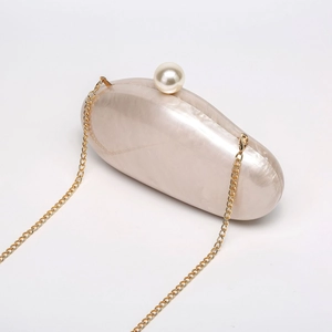 Detailed shot of pearlescent acrylic shell clutch with gold chain and large pearl clasp