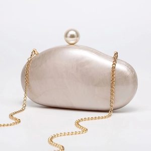 Detail of champagne pearl evening clutch with marble texture and round pearl clasp fastener