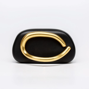 Close-up of matte black leather evening bag featuring a large irregular gold metal ring