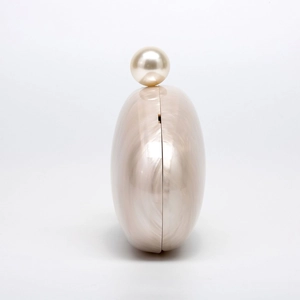 Detail of acrylic shell clutch with creamy marbled finish and large pearl clasp detail