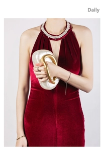 Detail view of pearl white acrylic shell clutch bag with thick glossy gold handle