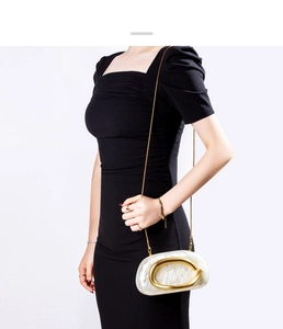 Detail of ivory shell evening clutch with gold C-shaped metal hardware and chain strap
