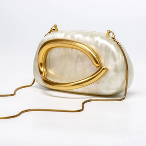Detailed close-up of shell-textured acrylic evening bag with gold C-handle and chain