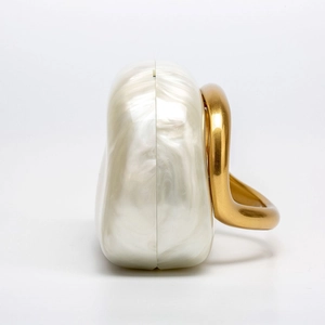 Detail of pearl white shell acrylic clutch with golden metal handle and side opening