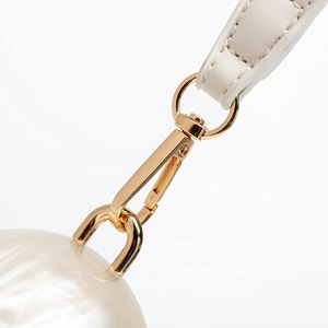 Detailed close-up of gold lobster clasp, white leather strap and pearlescent ball bag