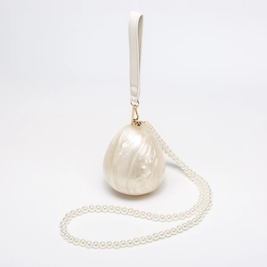 Detail of white shell textured evening clutch with pearlescent finish and pearl chain