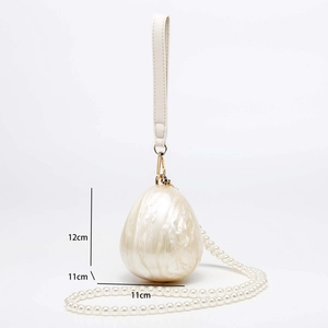 Detail showing 12cm height of egg-shaped shell evening bag with pearl chain strap