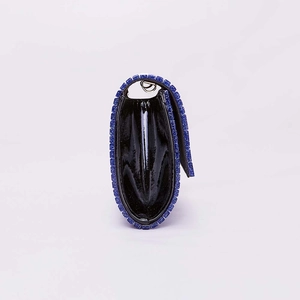 Detail of black acrylic evening clutch featuring blue glitter trim and side accordion folds