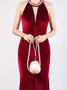 Detail of white shell acrylic evening bag with long pearl strap on velvet dress