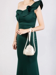 Detail of heart-shaped pearlescent acrylic clutch with pearl chain and leather strap