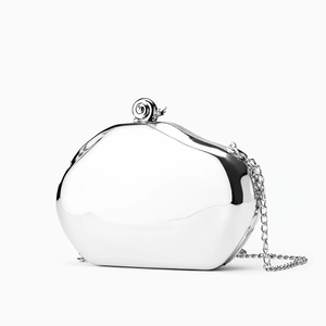 Macro detail of silver mirror hard shell evening bag with unique snail-shaped clasp