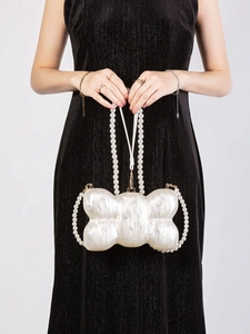 Detail view of white acrylic bow clutch with pearl handles and mother-of-pearl texture