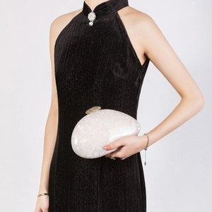 Elegant white pearlescent shell clutch bag with gold rhinestone buckle held by model
