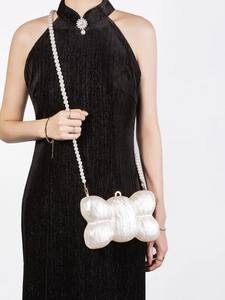 Detail of white pearlescent acrylic shell evening bag with decorative faux pearl strap