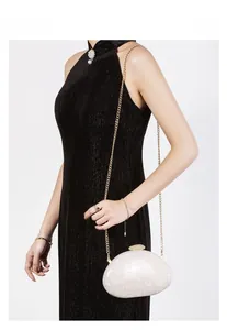 Detail of elegant shell-textured acrylic evening clutch with gold chain and diamond clasp