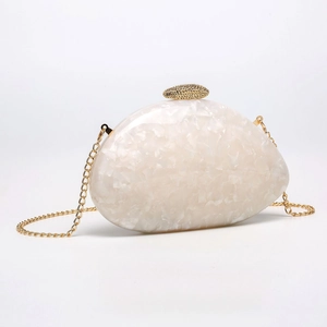 Macro detail of pearlescent marble texture on shell-shaped evening clutch with gold chain