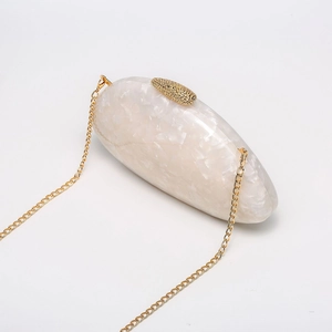 Macro detail of white marble acrylic shell clutch bag with gold chain and top metal clasp