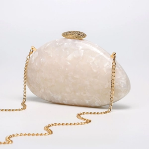 Macro detail of ivory shell-textured acrylic evening clutch with gold metal hardware