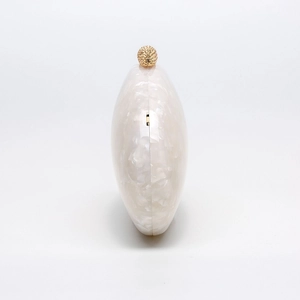 Detail of pearl marble acrylic evening clutch featuring a textured gold spherical clasp