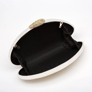 Detail view of white shell evening clutch with gold leaf clasp and black interior