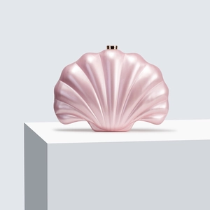 Macro shot of seashell-shaped acrylic evening clutch in pearlescent pink with gold clasp